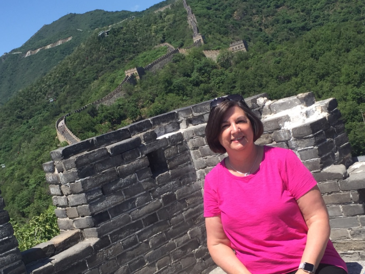 An image of Susan in a bright shirt with the Great Wall of China in the background