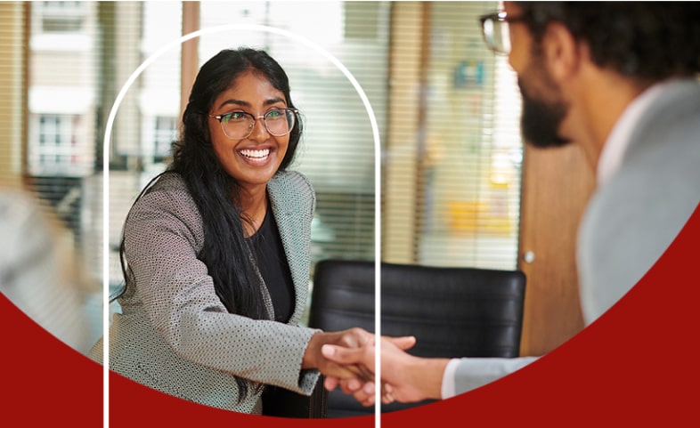 Smiling woman at her desk interacting with man on the other side of the desk