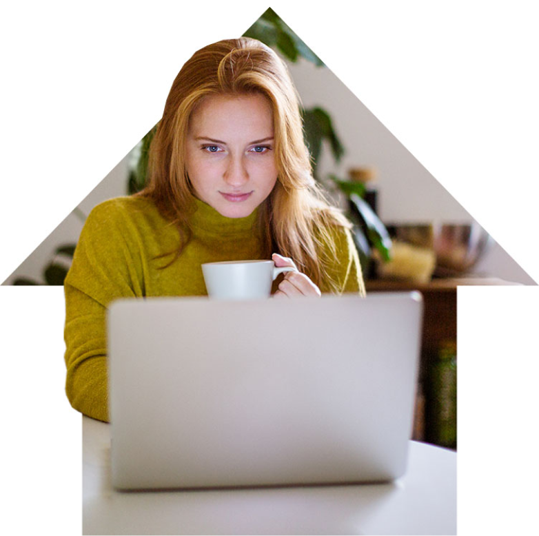 Woman sitting in front of her laptop, concentrating on the screen with a coffee cup in her hand