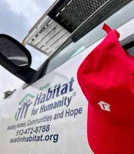 A white Habitat for Humanity van with a red Realtor.com cap.