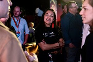 A happy Realtor.com employee at work, smiling with her arms crossed, as she has a discussion at an event.