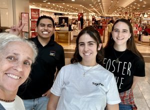 Four smiling people in front of a department store