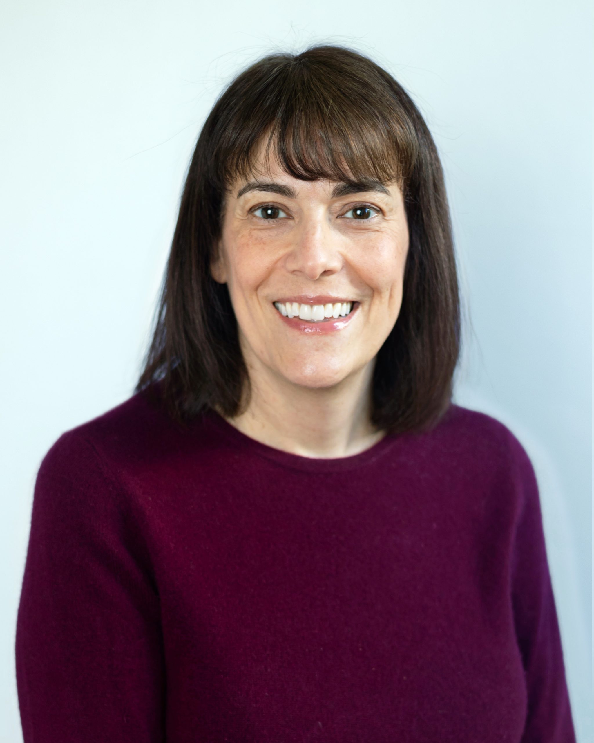 A headshot of a woman with brown hair and a smile.