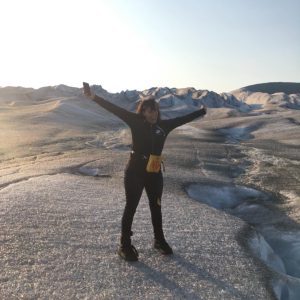 A woman with her arms raised triumphantly at the top of a mountain.